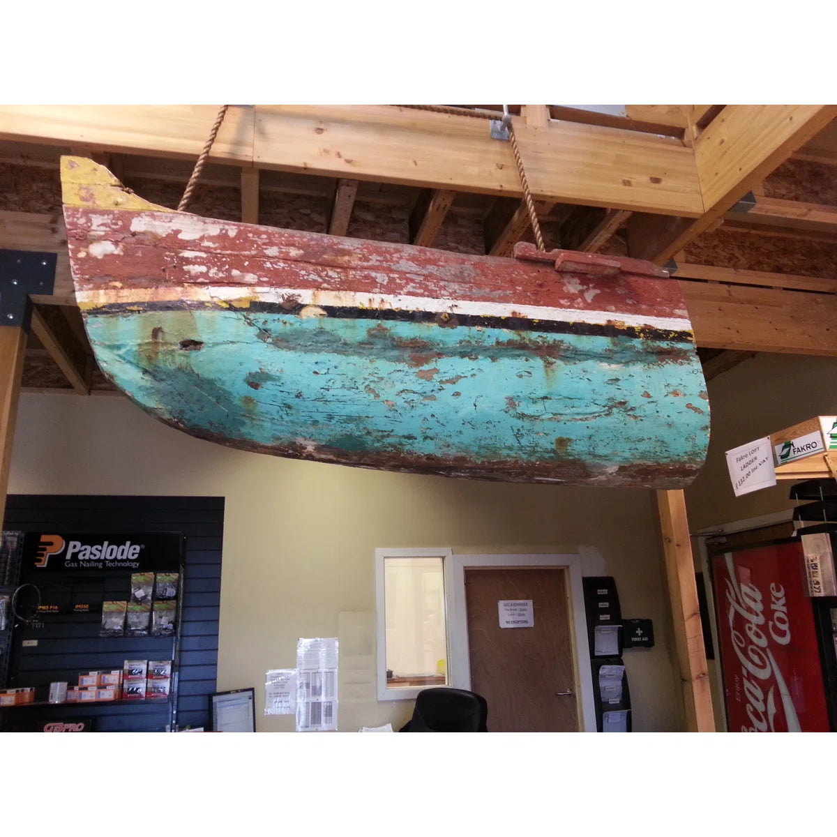 Rustic, turquoise and red metal object hanging from a ceiling in an indoor setting.