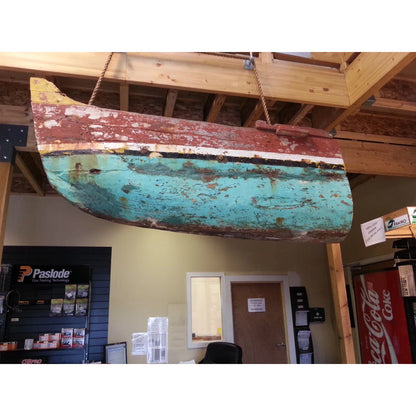 Rustic, turquoise and red metal object hanging from a ceiling in an indoor setting.