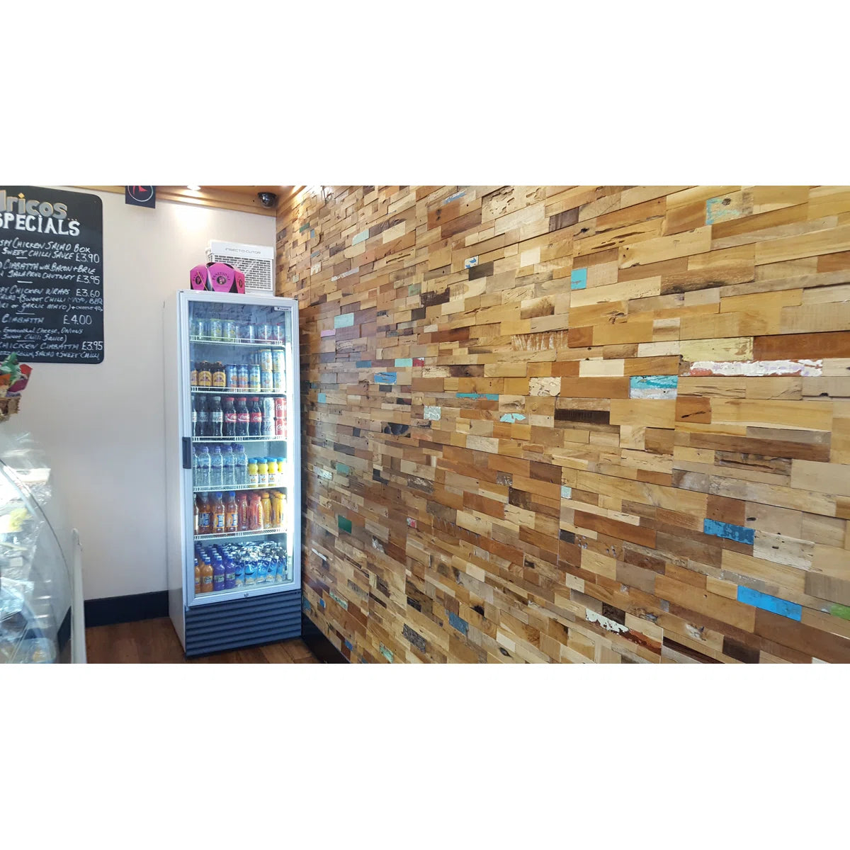 Fridge stocked with drinks against a wooden wall in a casual setting